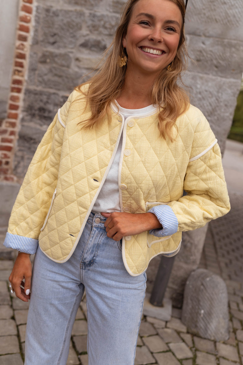 Veste matelassée à doublure rayée portée par une femme, vue de face, sourire, doublure bleue