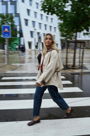 Veste souple à revers velours beige portée par une femme, en marchant, rue, jean foncé