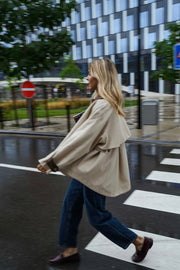 Veste souple à revers velours beige portée par une femme, en marchant, rue, immeubles