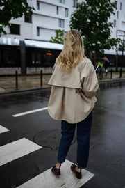 Veste souple à revers velours beige portée par une femme, vue de dos, passage piéton, jean foncé