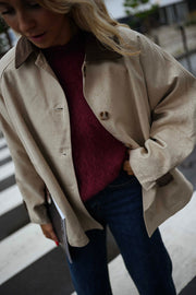 Veste souple à revers velours beige portée par une femme, vue rapprochée, pull bordeaux, poche