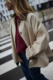 Veste souple à revers velours beige portée par une femme, vue rapprochée, pull bordeaux, passage piéton