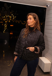 Veste matelassée à doublure léopard portée par une femme, vue rapprochée, jean, main dans la poche