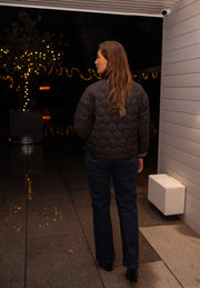 Veste matelassée à doublure léopard portée par une femme, vue de dos, jean foncé, terrasse