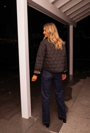 Veste matelassée à doublure léopard portée par une femme, silhouette entière, jean foncé, terrasse