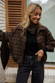 Veste à carreaux à poches portée par une femme, vue rapprochée, carreaux marron, col roulé noir