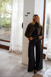 Veste à carreaux zippée portée par une femme, vue de face, baie vitrée, pantalon noir