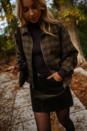 Veste à carreaux zippée portée par une femme, vue de trois-quarts, allée pavée, jupe noire
