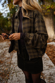 Veste à carreaux zippée portée par une femme, vue de dos, allée pavée, téléphone