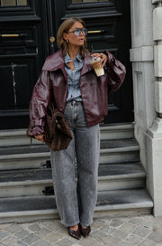Veste en simili cuir loose portée par une femme, silhouette entière, sur des marches