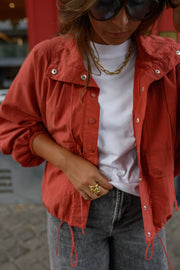 Veste courte déperlante portée par une femme, vue rapprochée, collier, t-shirt blanc, lunettes de soleil
