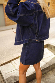 Veste en jean courte portée par une femme, vue de dos, jupe en jean, marches
