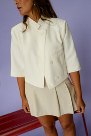 Veste courte à manches courtes portée par une femme, vue rapprochée, col, jupe plissée