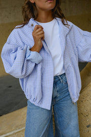 Veste à carreaux bouffante portée par une femme, vue rapprochée, main sur le col, t-shirt blanc