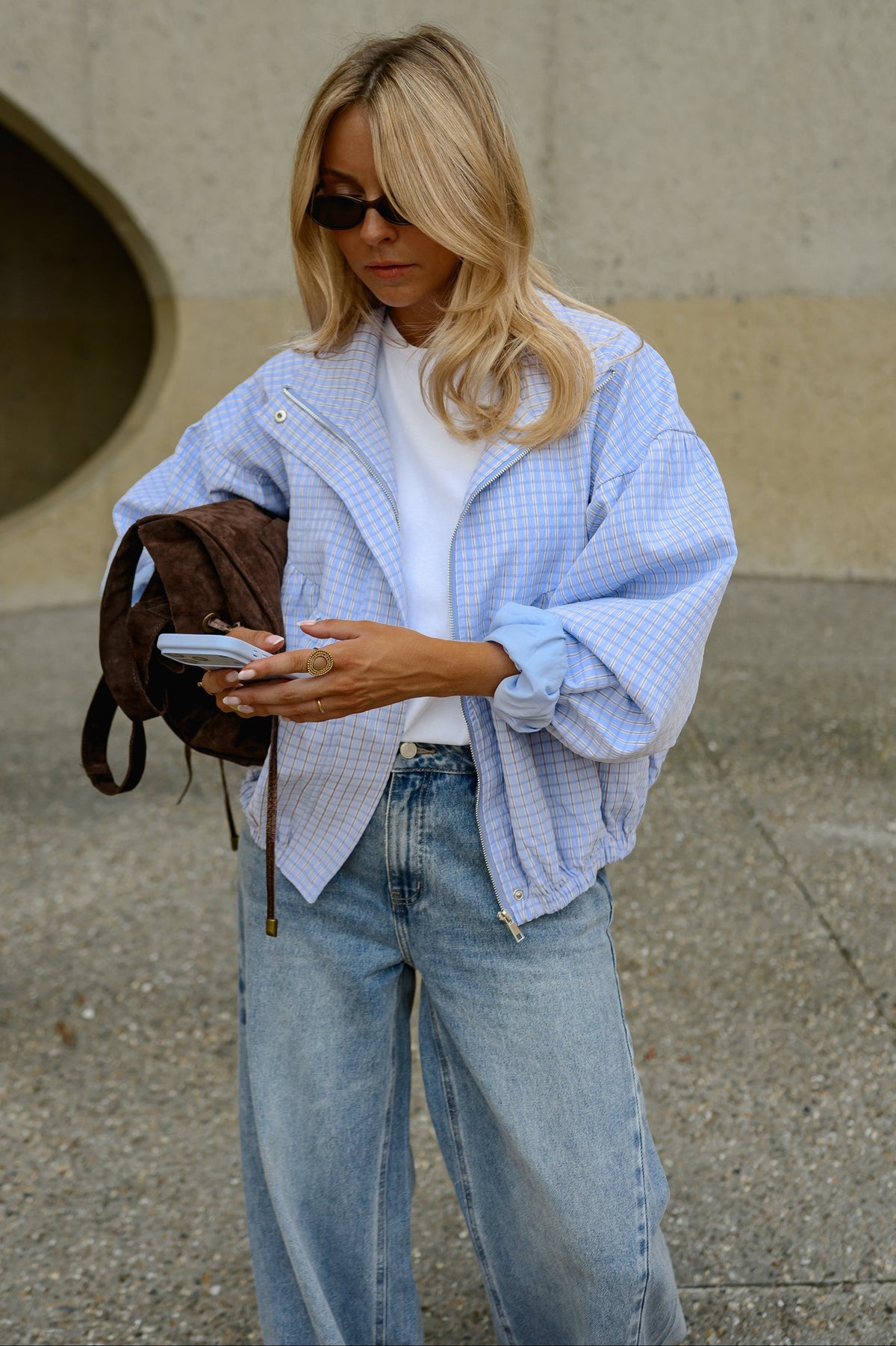 Veste à carreaux bouffante portée par une femme, vue de trois-quarts, t-shirt blanc, jean bleu, sac marron