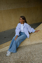 Veste à carreaux bouffante portée par une femme, assise, assise sur un rebord, baskets, jean large