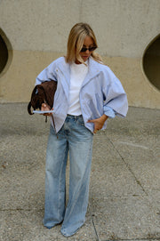 Veste à carreaux bouffante portée par une femme, silhouette entière, lunettes de soleil, sac marron, jean large