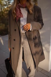 Veste longue boutonnée doublée grise portée par une femme, vue rapprochée, manteau long, pantalon beige