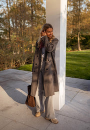 Veste longue boutonnée doublée grise portée par une femme, vue de trois-quarts, manteau long, terrasse