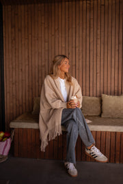 Veste ample à franges portée par une femme, assise, assise sur le banc, jambes croisées