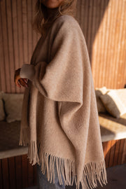 Veste ample à franges portée par une femme, vue de dos, franges, coussins