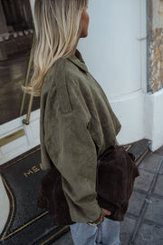 Veste loose à zip doré kaki portée par une femme, vue de profil, sac marron, cheveux blonds