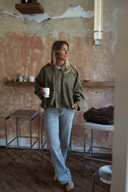 Veste loose à zip doré kaki portée par une femme, vue de face, café, étagère