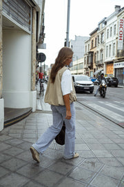 Veste sans manches à poches beige portée par une femme, en marchant, rue, sac noir