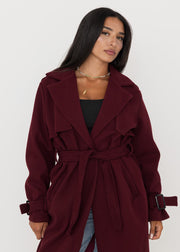 Trench oversize bordeaux à ceinture — vue portée de face, ouvert sur un haut noir et jean clair