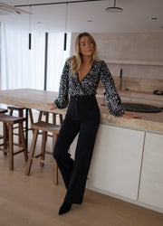 Body à paillettes cache-cœur porté par une femme, silhouette entière, pantalon noir, plan de travail