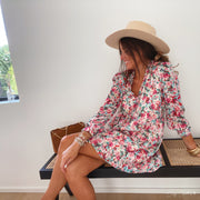 Robe fleurie à lurex portée par une femme, assise, banc en bois, sandales