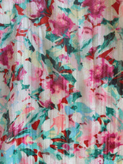 Robe fleurie à lurex portée par une femme, vue rapprochée, imprimé floral rose et turquoise, tissu