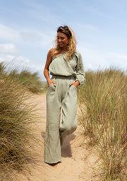 Combinaison asymétrique à poches portée par une femme, vue de face, dunes, herbes