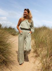 Combinaison asymétrique à poches portée par une femme, vue de trois-quarts, dunes, sourire