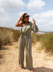 Combinaison asymétrique à poches portée par une femme, vue de face, plage, lunettes de soleil