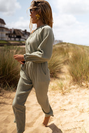 Combinaison asymétrique à poches portée par une femme, vue de trois-quarts, herbes hautes, de côté
