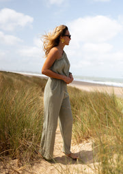 Combinaison asymétrique à poches portée par une femme, vue de face, plage, herbes
