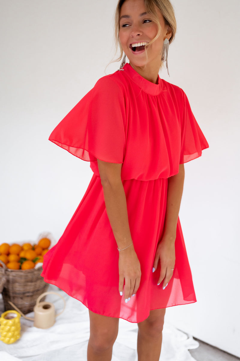 Robe courte fluide portée par une femme, vue de face, mur blanc, manches volantées