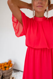 Robe courte fluide portée par une femme, vue rapprochée, bras levé, col montant