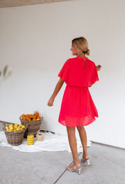 Robe courte fluide portée par une femme, vue de dos, mur blanc, paniers