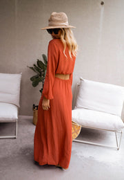 Robe longue à côtés ouverts portée par une femme, vue de dos, chapeau de paille, fauteuil blanc