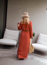 Robe longue à côtés ouverts portée par une femme, vue de dos, salon de jardin, chapeau