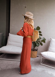 Robe longue à côtés ouverts portée par une femme, vue de profil, plante verte, chapeau