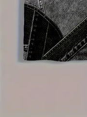 Vue rapprochée de l’imprimé patchwork noir et gris avec surpiqûres contrastantes.