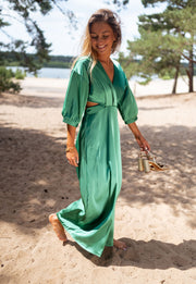 Robe fluide à manches trois-quarts portée par une femme, vue de face, plage, sandales à la main