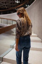 Gilet léopard boutonné porté par une femme, vue de dos, cheveux longs, jean