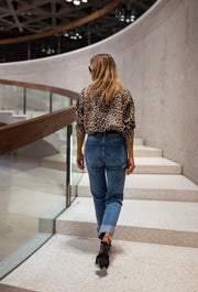 Gilet léopard boutonné porté par une femme, vue de dos, escalier, cheveux longs, rampe