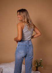 Top moulant épaules échancrées porté par une femme, vue de dos, fond beige, jean