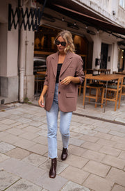 Blazer ample à épaulettes porté par une femme, silhouette entière, terrasse, jean clair
