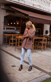 Blazer ample à épaulettes porté par une femme, silhouette entière, de loin, terrasse